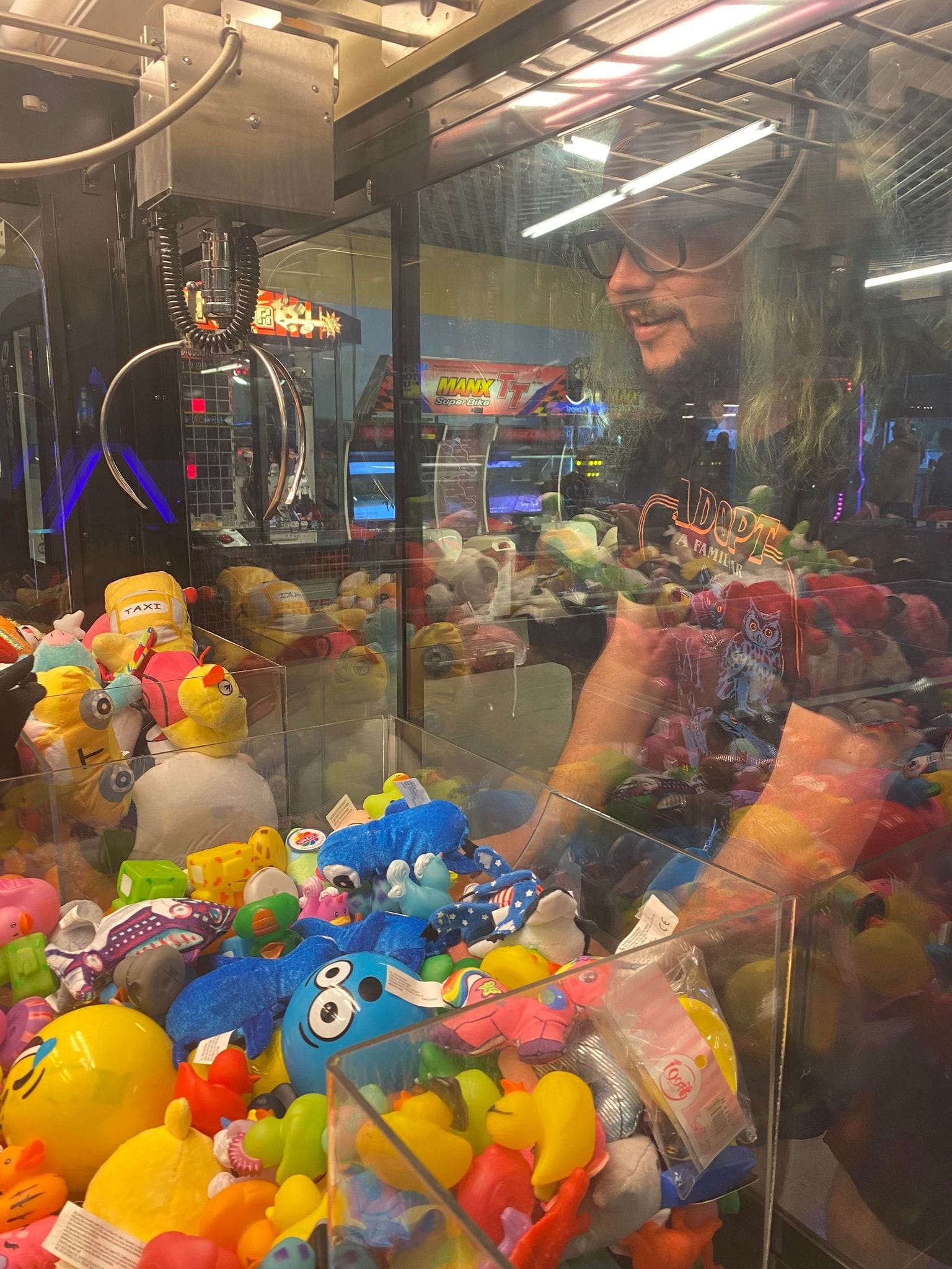 A man with green hair plays an arcade claw game, Photo 1